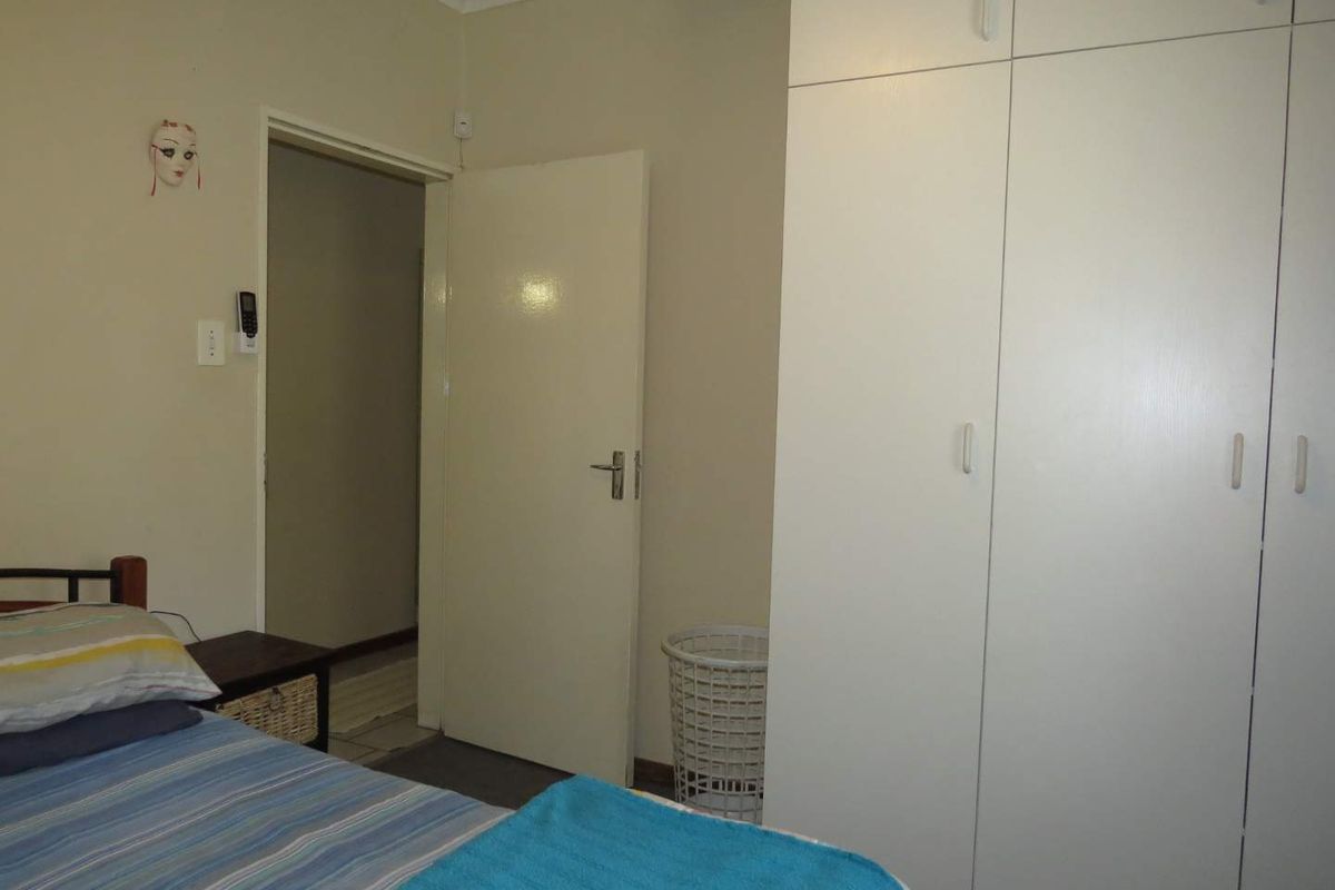 A bedroom featuring built-in cupboards and a doorway leading to an adjacent hallway.