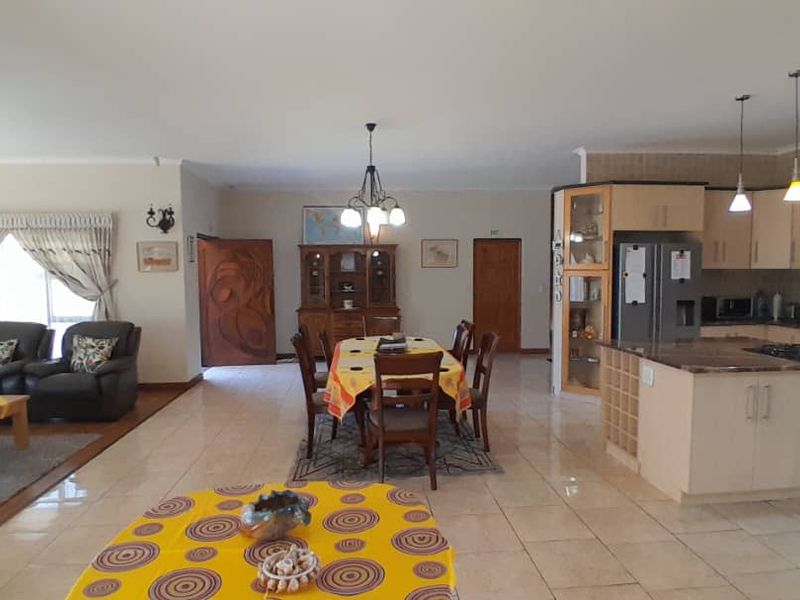 Spacious open-plan living area featuring a functional kitchen with island, gas hob, and tiled flooring, seamlessly connecting to the dining and lounge spaces.