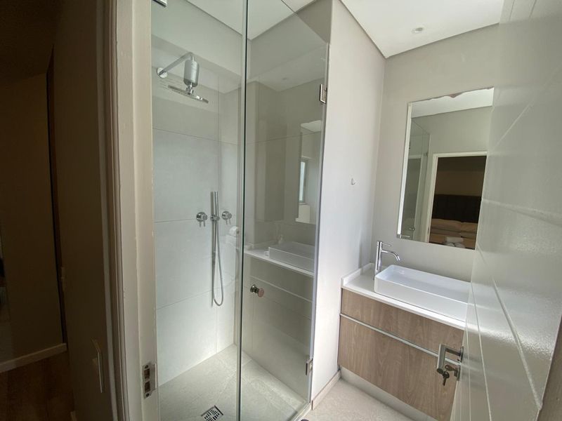 Modern bathroom featuring a glass-enclosed shower, contemporary vanity with a vessel sink, and clean neutral tiling.