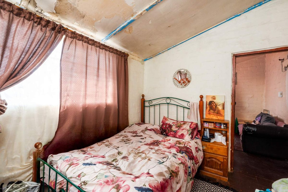 A bedroom featuring a sloped ceiling with visible signs of water damage and peeling paint, requiring significant repair and refurbishment.