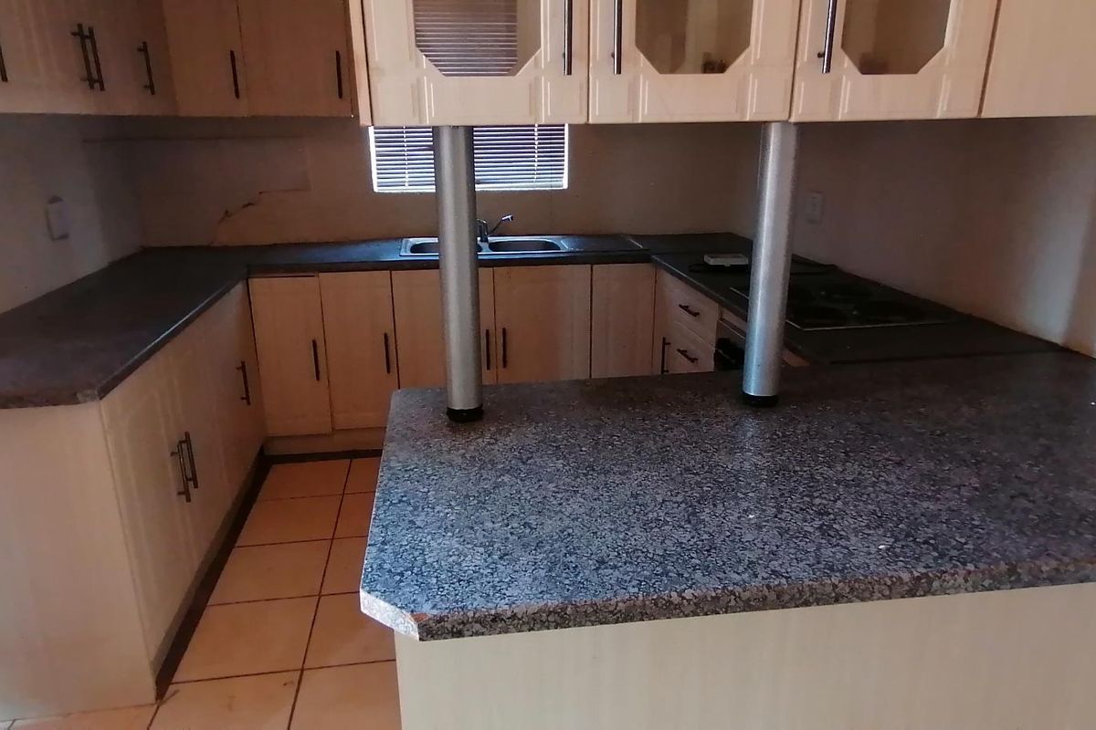 A functional kitchen featuring laminate cabinetry, granite countertops, a double basin sink, and a built-in hob with an integrated breakfast nook.