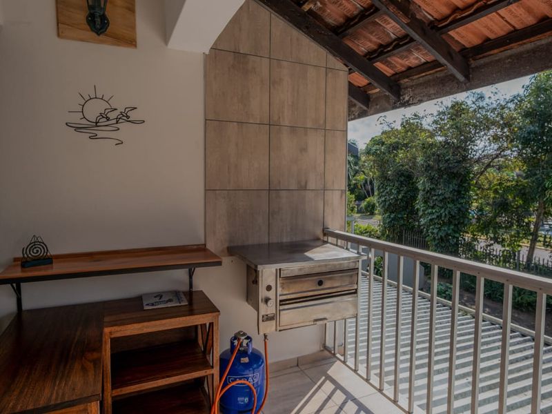 Covered balcony featuring a built-in braai, tiled wall accents, and a metal balustrade, offering an outdoor entertainment space with garden views.