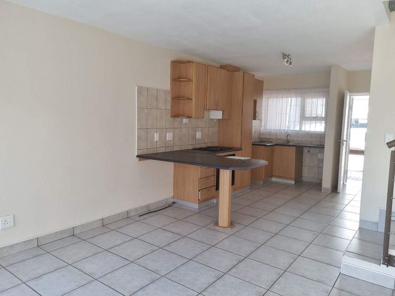 A functional kitchen featuring laminate cabinetry, tiled backsplash, and ceramic flooring, offering a clean, blank canvas for potential modern updates.
