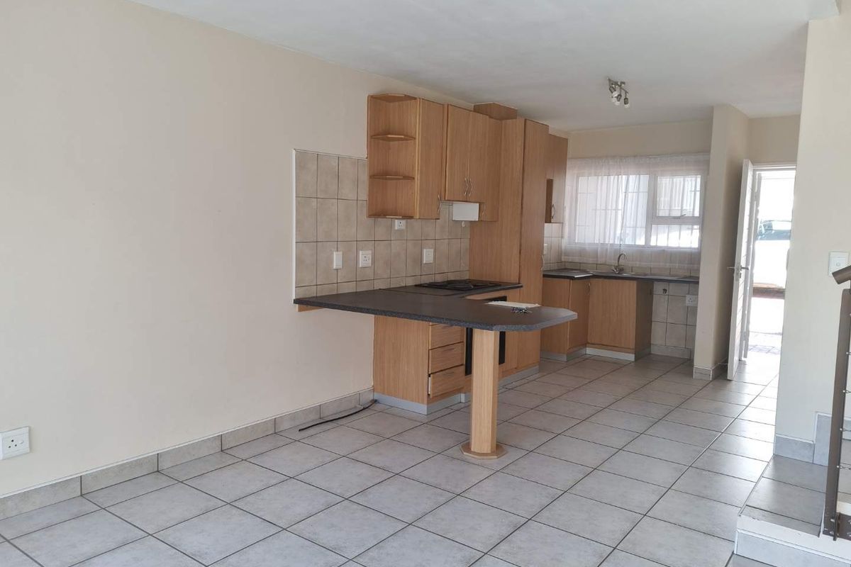 A functional kitchen featuring laminate cabinetry, tiled backsplash, and ceramic flooring, offering a clean, blank canvas for potential modern updates.