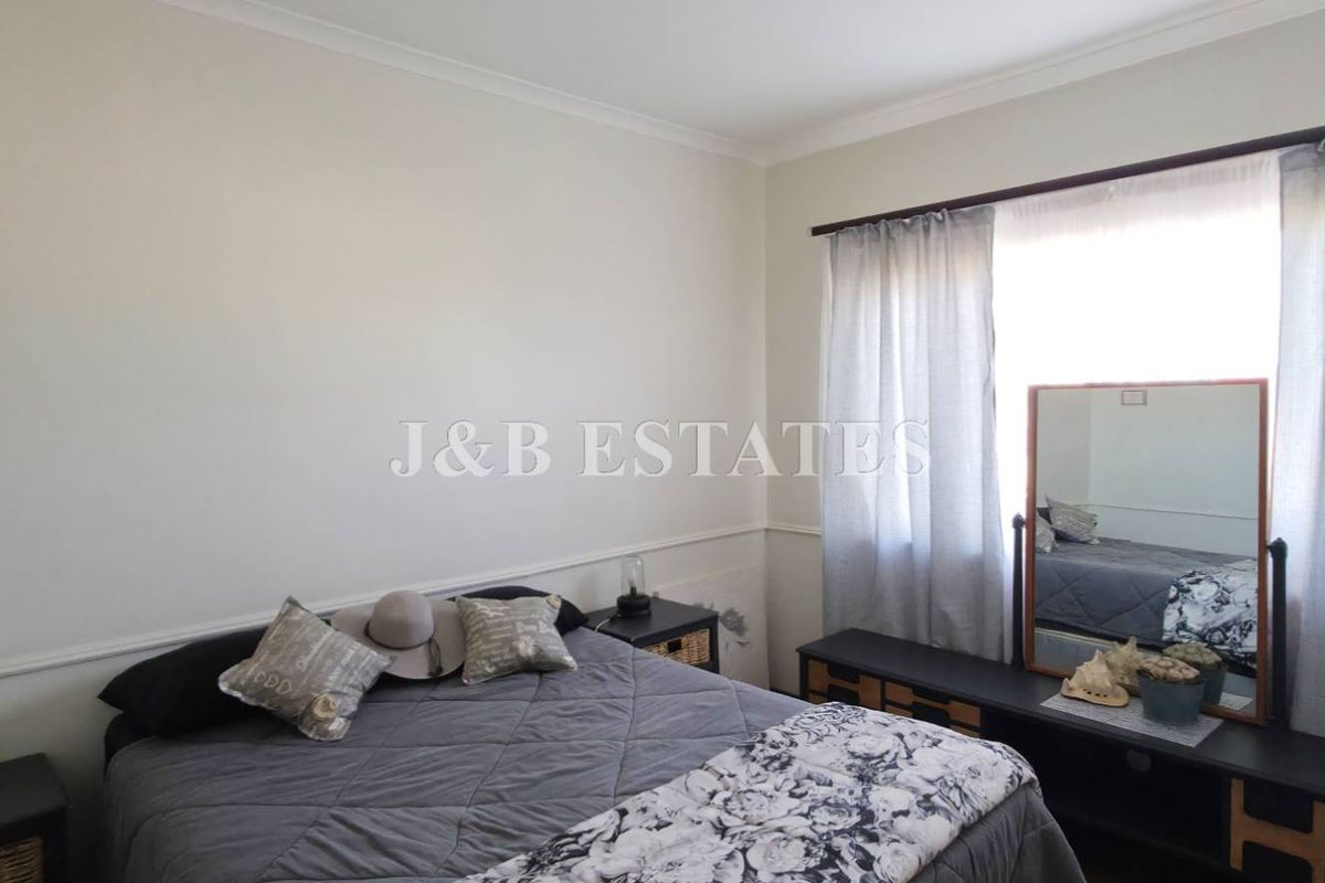 A bedroom featuring neutral walls with dado rail detailing and a large window with curtain treatments.
