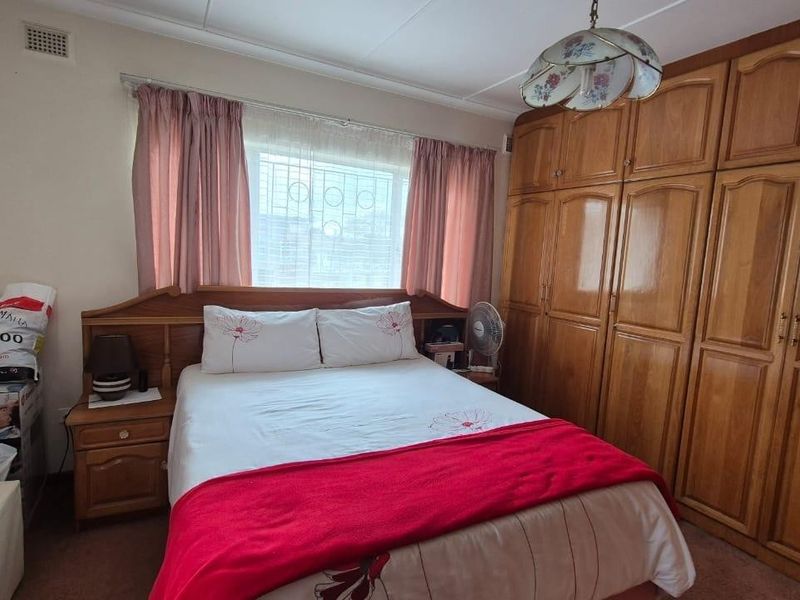A bedroom featuring extensive built-in wooden cabinetry and a window fitted with security bars.