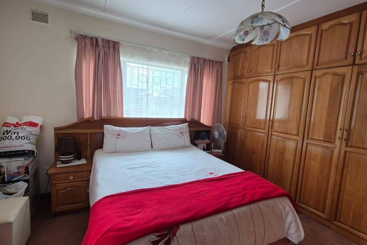 A bedroom featuring extensive built-in wooden cabinetry and a window fitted with security bars.