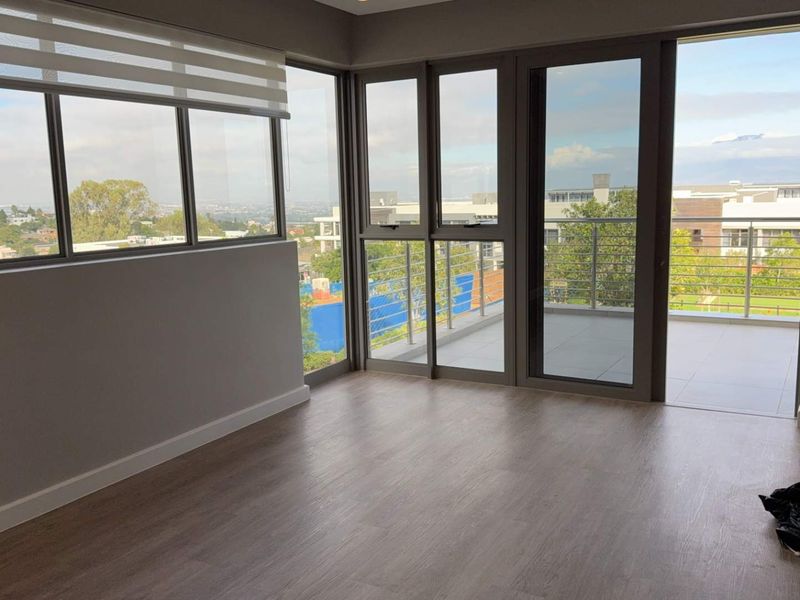 Bright and modern living area featuring laminate flooring, large windows, and direct access to a private balcony with scenic views.