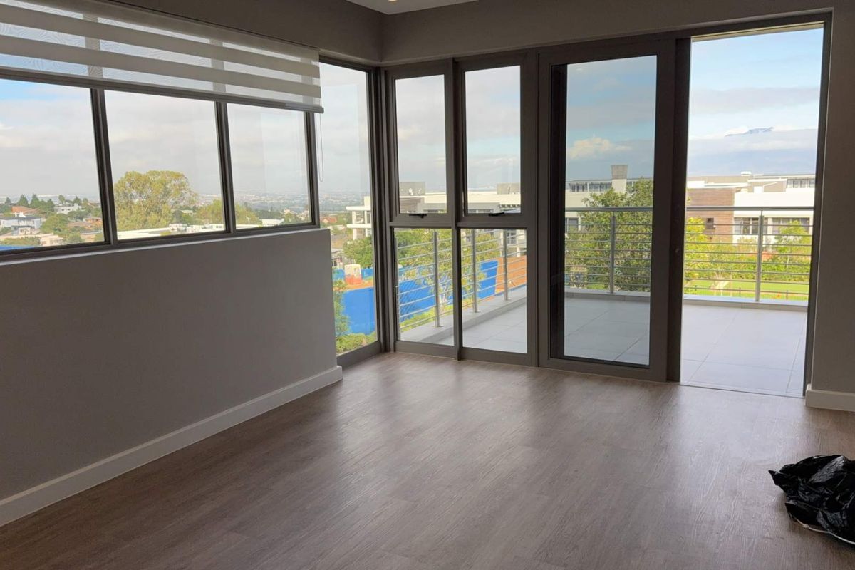Bright and modern living area featuring laminate flooring, large windows, and direct access to a private balcony with scenic views.
