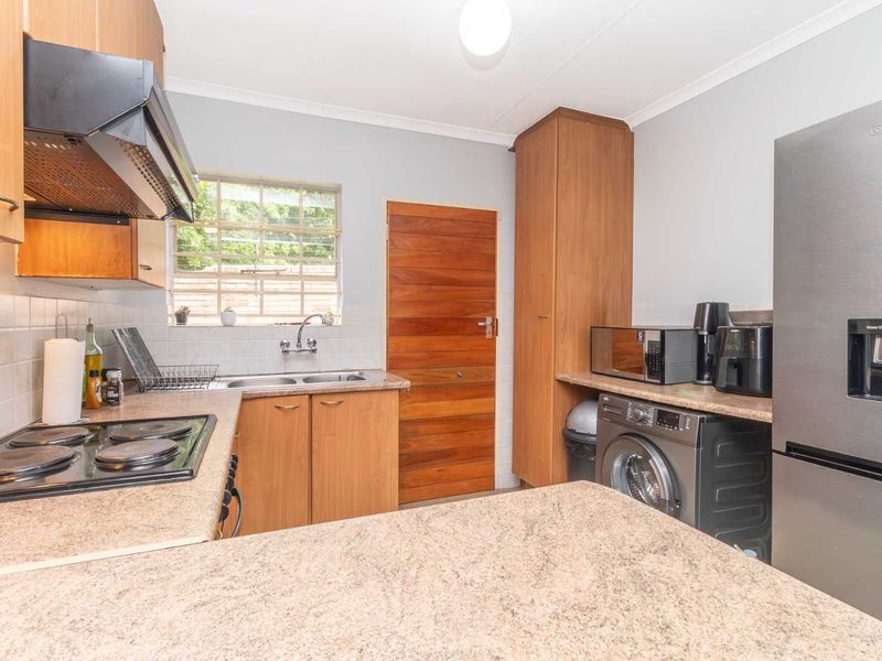 Functional kitchen featuring laminate cabinetry, granite countertops, a double basin sink, electric hob with extractor, and dedicated plumbing for a washing machine.