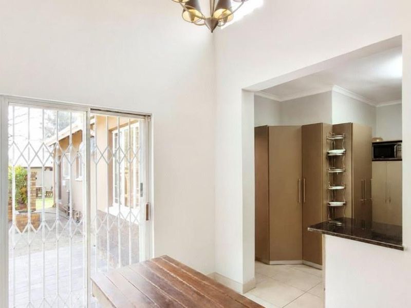Open plan living area featuring tiled flooring, a sliding door with security gate, and a view into the adjacent kitchen with built-in cabinetry.