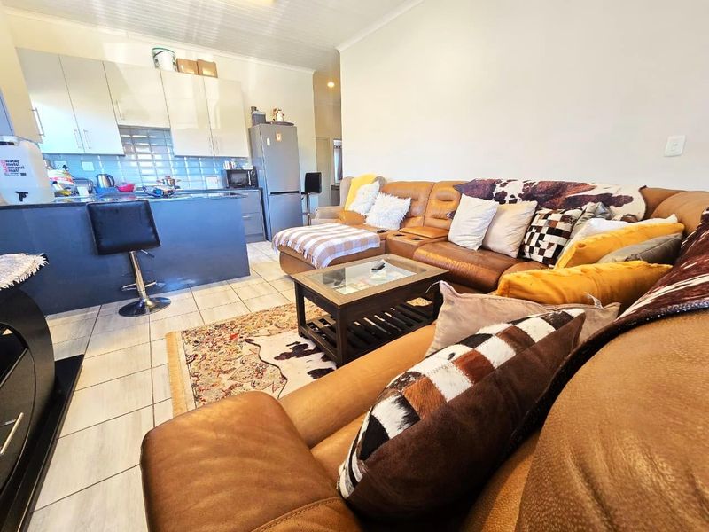 Open plan living area featuring a modern kitchen with island, tiled flooring, and a combined lounge space.
