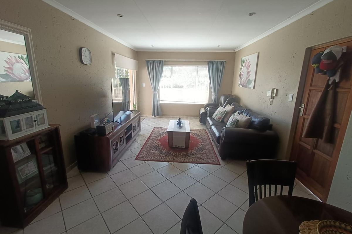 A comfortable living room featuring tiled flooring, recessed downlighting, and natural light through a large window with blinds.