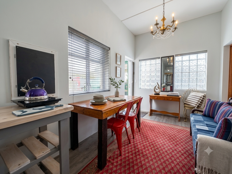 A bright living area featuring vaulted ceilings, a classic chandelier, glass block windows, and durable laminate flooring, offering a cozy and well-lit space.