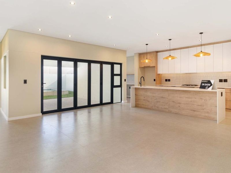 Spacious open-plan living and kitchen area featuring modern cabinetry, a large island, recessed lighting, and bi-fold doors leading to the outdoor space.