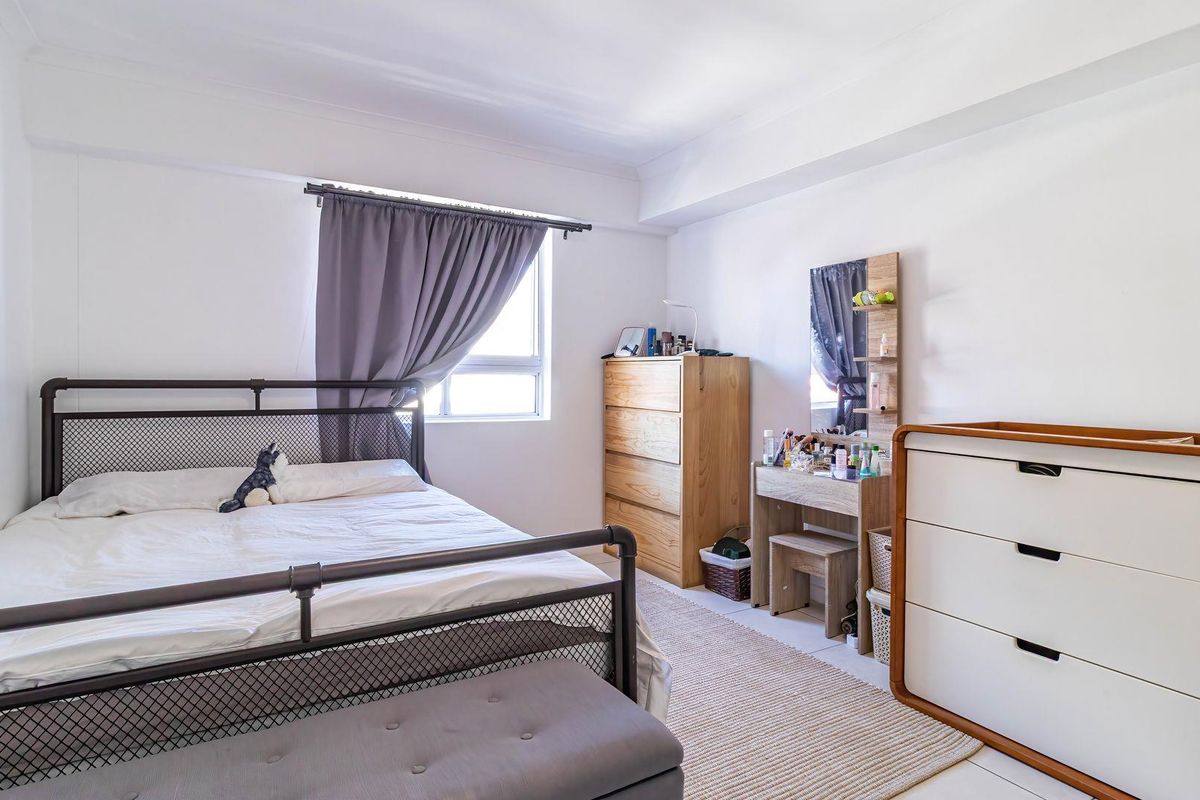 A bright and functional bedroom featuring neutral walls, tiled flooring, and a window with curtain track.