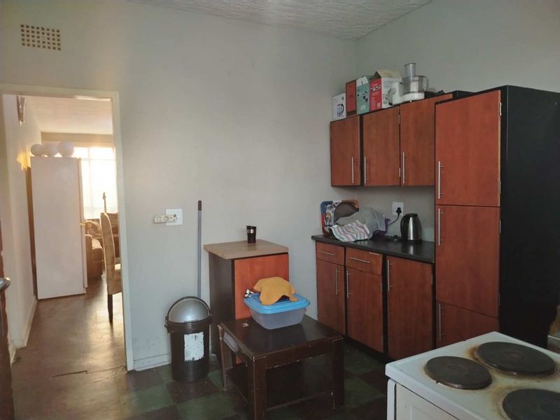 A compact kitchen featuring built-in wooden cabinetry, laminate countertops, and an electric stove, with direct access to the adjacent living area.