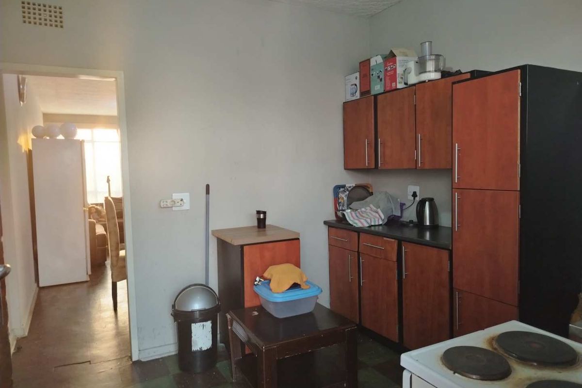 A compact kitchen featuring built-in wooden cabinetry, laminate countertops, and an electric stove, with direct access to the adjacent living area.