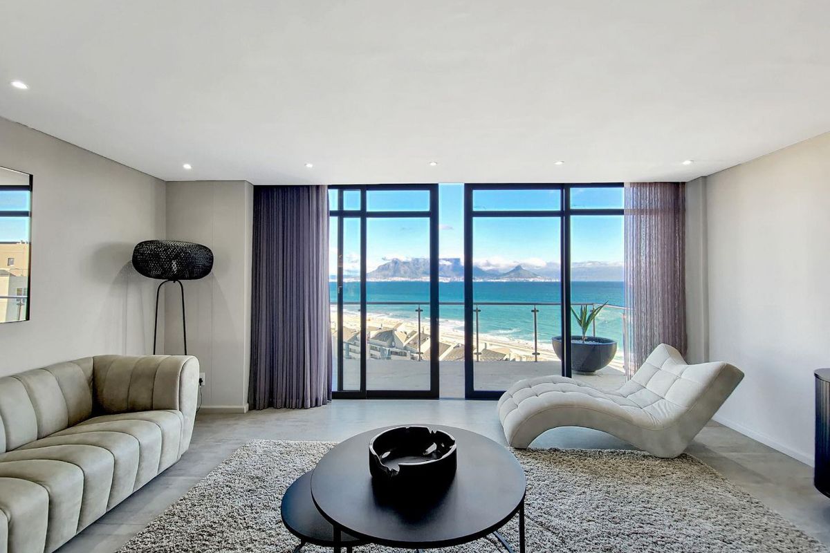 Spacious living area featuring floor-to-ceiling sliding glass doors that open to a balcony with panoramic ocean and mountain views.