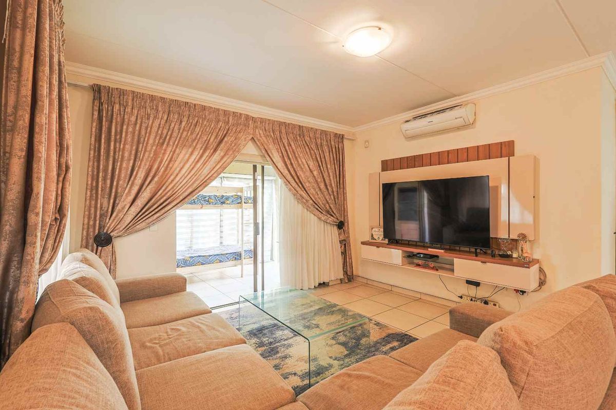 A comfortable living room featuring tiled flooring, a built-in media console, and a sliding glass door providing access to an outdoor patio area.