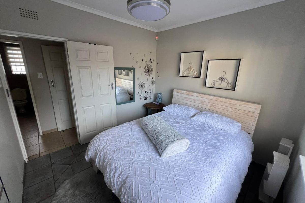 A bedroom featuring tiled flooring, a central flush mount light fixture, and direct access to an adjacent bathroom.
