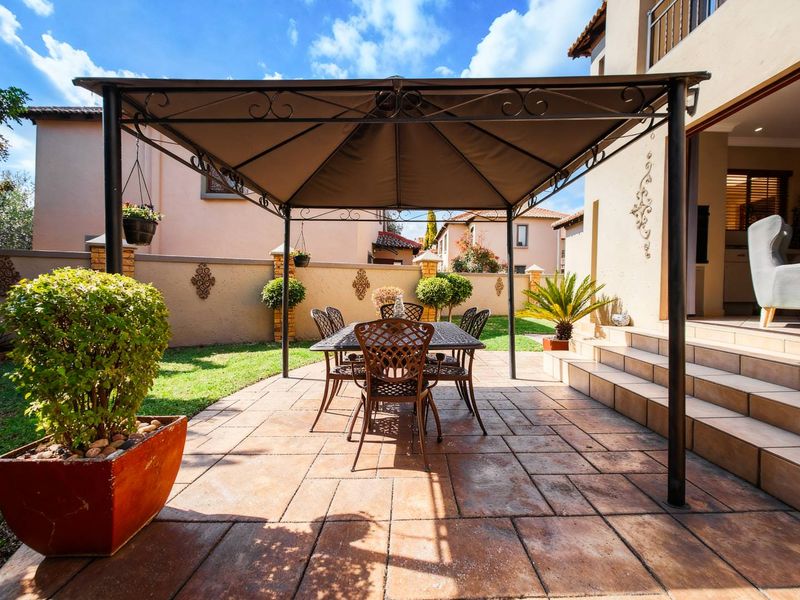 A well-maintained paved patio area featuring a metal gazebo, providing a comfortable outdoor space directly accessible from the main living area.