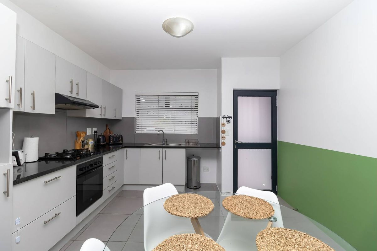 Modern kitchen featuring light grey cabinetry, black granite countertops, gas hob, built-in oven, and tiled flooring with a functional layout.