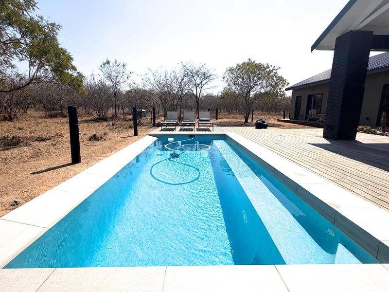 A modern rectangular swimming pool set within a timber deck, featuring clean lines and a clear view of the surrounding natural landscape.