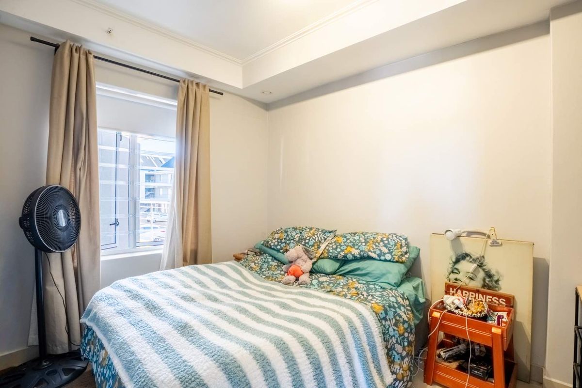 A functional bedroom featuring a recessed ceiling and a window equipped with security bars, providing natural light and ventilation.