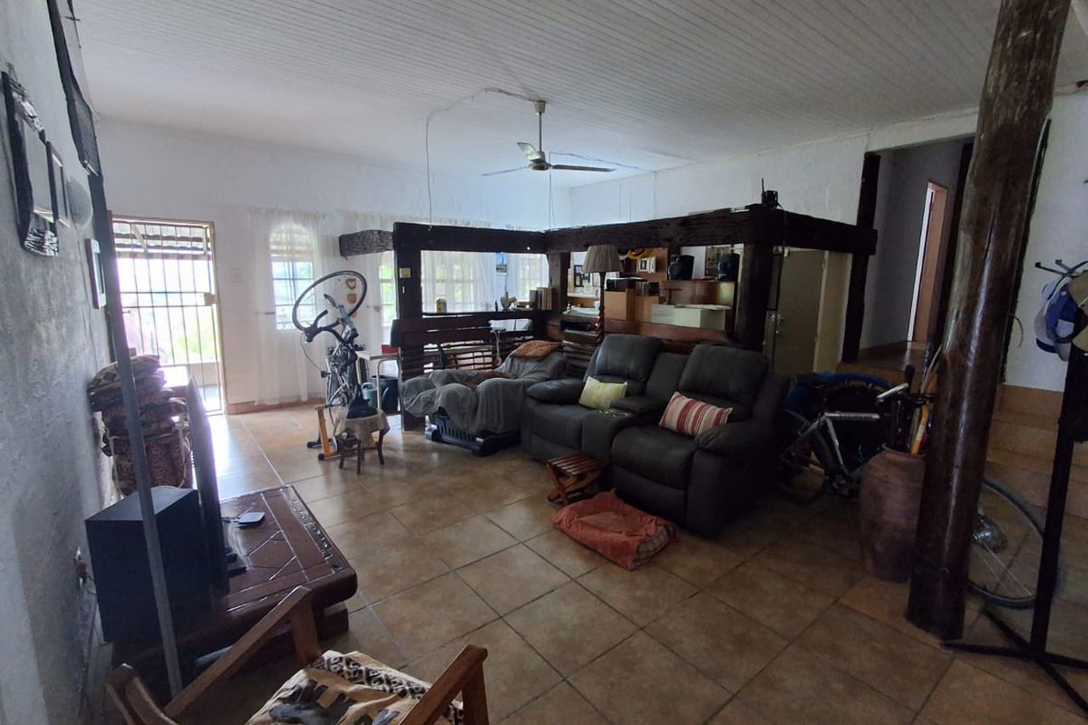 Spacious living area featuring tiled flooring, exposed timber ceiling beams, and a ceiling fan, providing a rustic and functional layout.