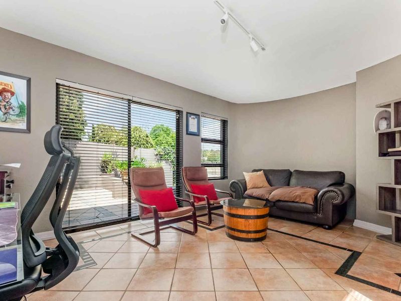 A bright living room featuring tiled flooring, track lighting, and large sliding glass doors that provide access to the outdoor patio area.