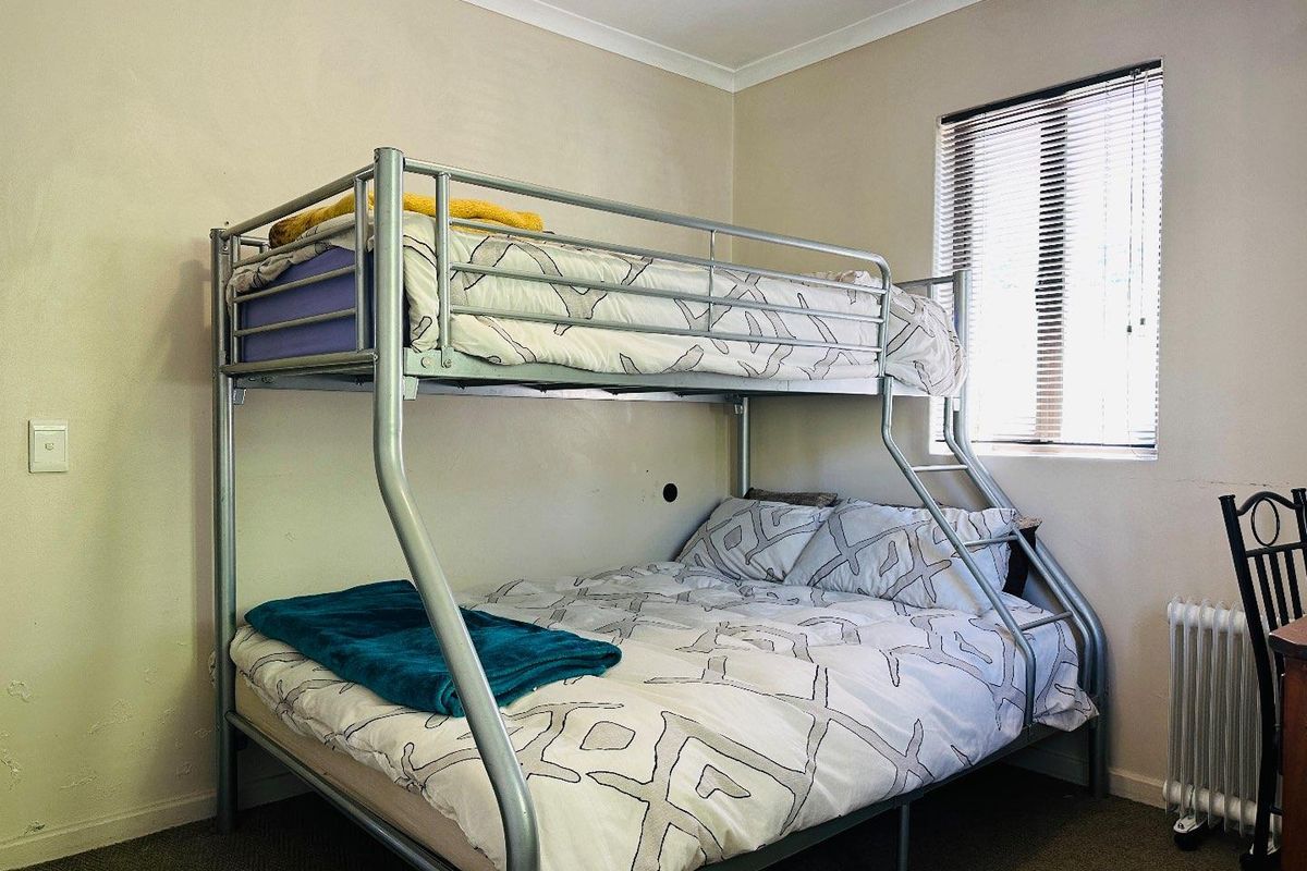 A functional bedroom featuring neutral walls, coving, and a window with fitted venetian blinds.