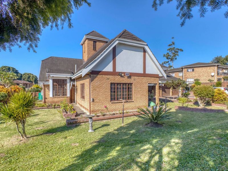 A well-maintained brick house exterior featuring a tiled roof, security bars on windows, and a landscaped garden with established lawn and brick edging.