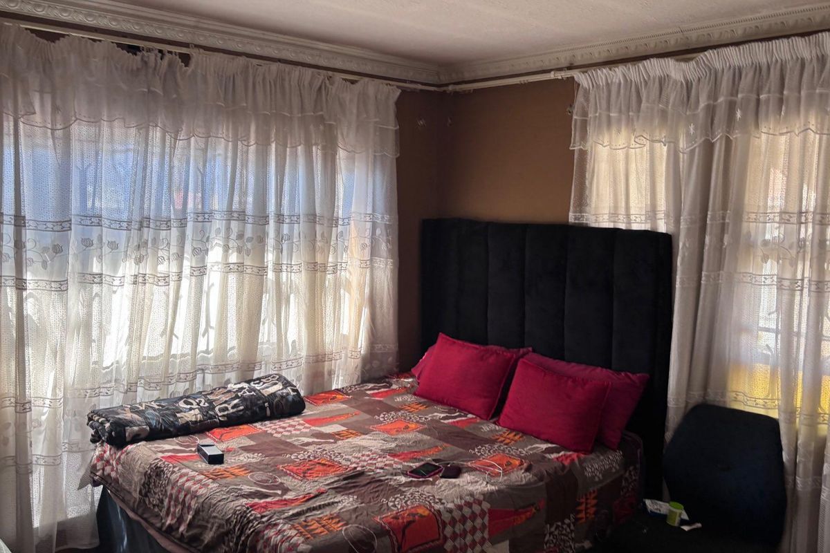 A bedroom featuring decorative ceiling cornicing and dual window treatments, providing a functional space with potential for modern updates.
