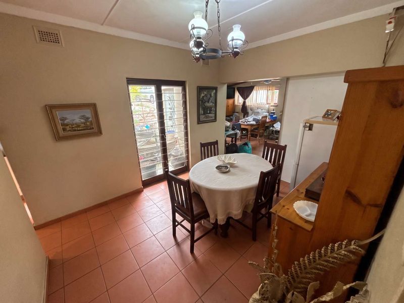 A dining area featuring tiled flooring, a glass panel door leading to the exterior, and a traditional ceiling light fixture.