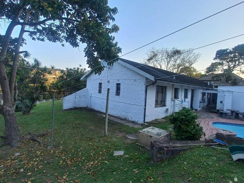 Rear view of the property featuring a swimming pool, paved patio area, and established garden space with a water storage tank.