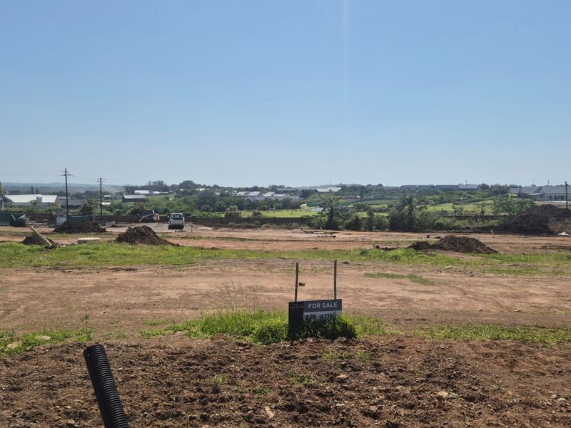 A view of a vacant residential plot of land with earthworks visible, situated in a developing estate.