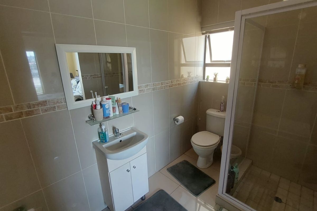 A functional bathroom featuring a vanity basin, a toilet, and a glass-enclosed shower with full-height wall tiling.