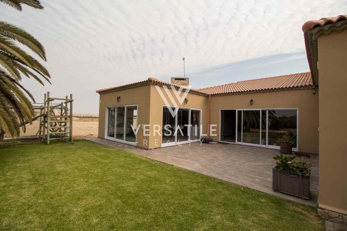 Rear view of the property featuring a tiled patio area, sliding glass doors, and a well-maintained lawn.