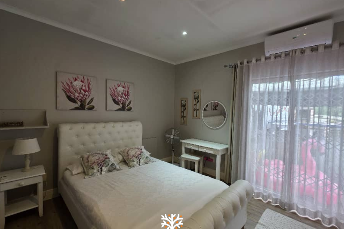 A well-maintained bedroom featuring recessed ceiling lighting, wood-look flooring, and a wall-mounted air conditioning unit with direct access to an outdoor area.