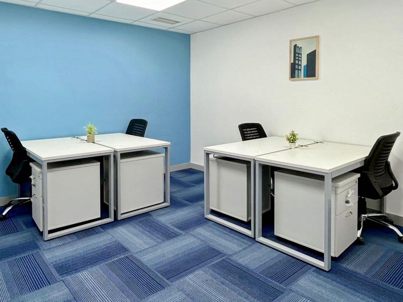 A clean, modern office space featuring blue and white walls, carpeted flooring, and a suspended ceiling with recessed lighting.
