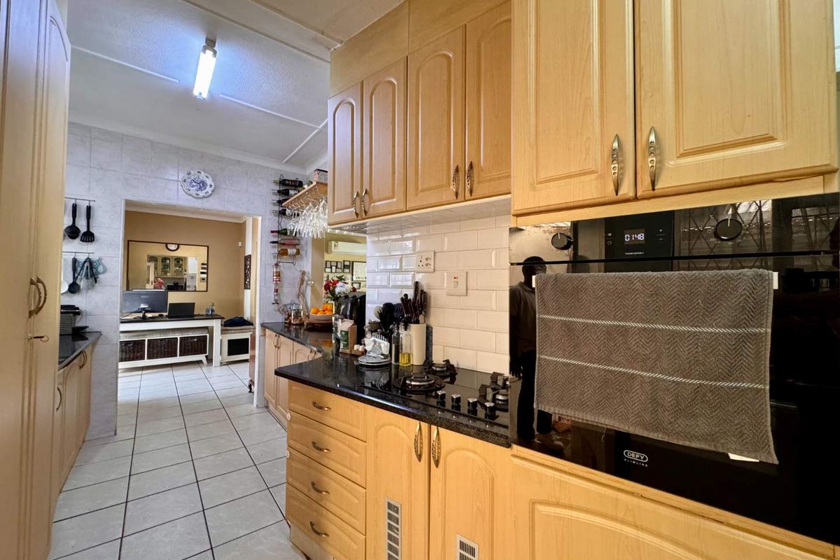 A functional kitchen featuring light wood cabinetry, granite countertops, a gas hob, and a built-in oven with a classic subway tile backsplash.