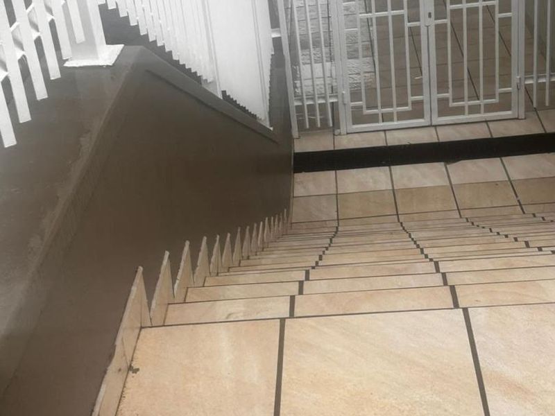 A tiled staircase leading to a secure metal entrance gate with white metal balustrades.