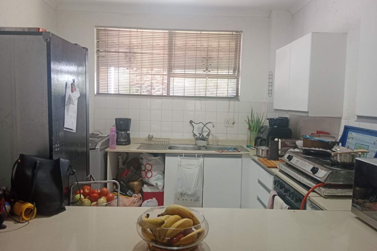 A functional kitchen featuring built-in cabinetry, a double basin sink, tiled splashback, and a gas hob, offering potential for modernization.