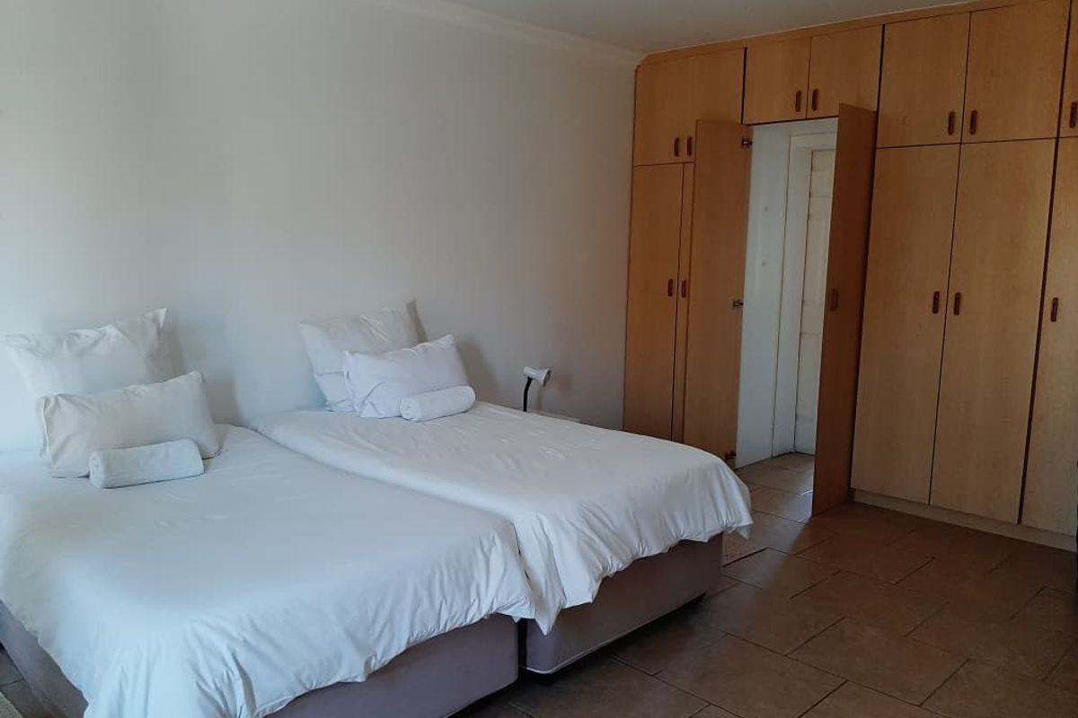 A bedroom featuring built-in wooden cupboards and tiled flooring, providing functional storage space.