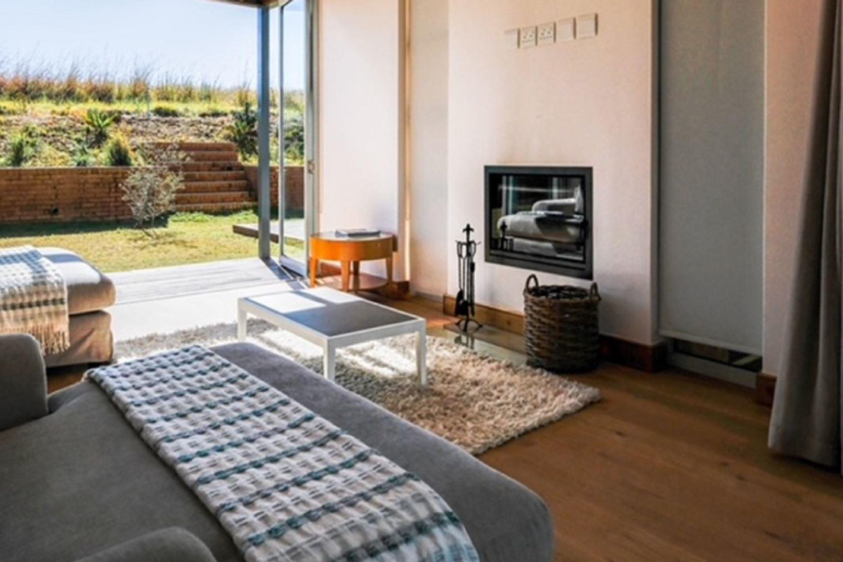 A bright living room featuring a built-in fireplace, timber flooring, and large glass sliding doors opening onto a private garden patio.