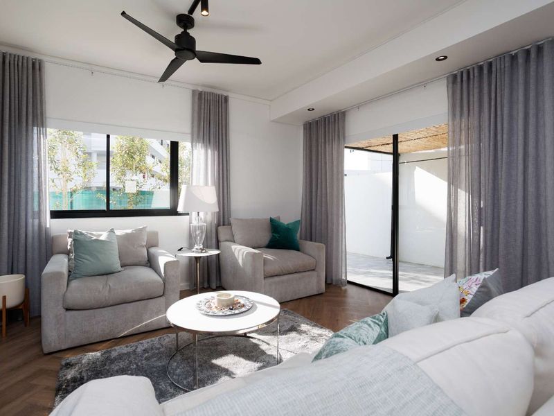 A bright and modern living room featuring herringbone flooring, recessed lighting, a ceiling fan, and large sliding glass doors leading to an outdoor patio area.