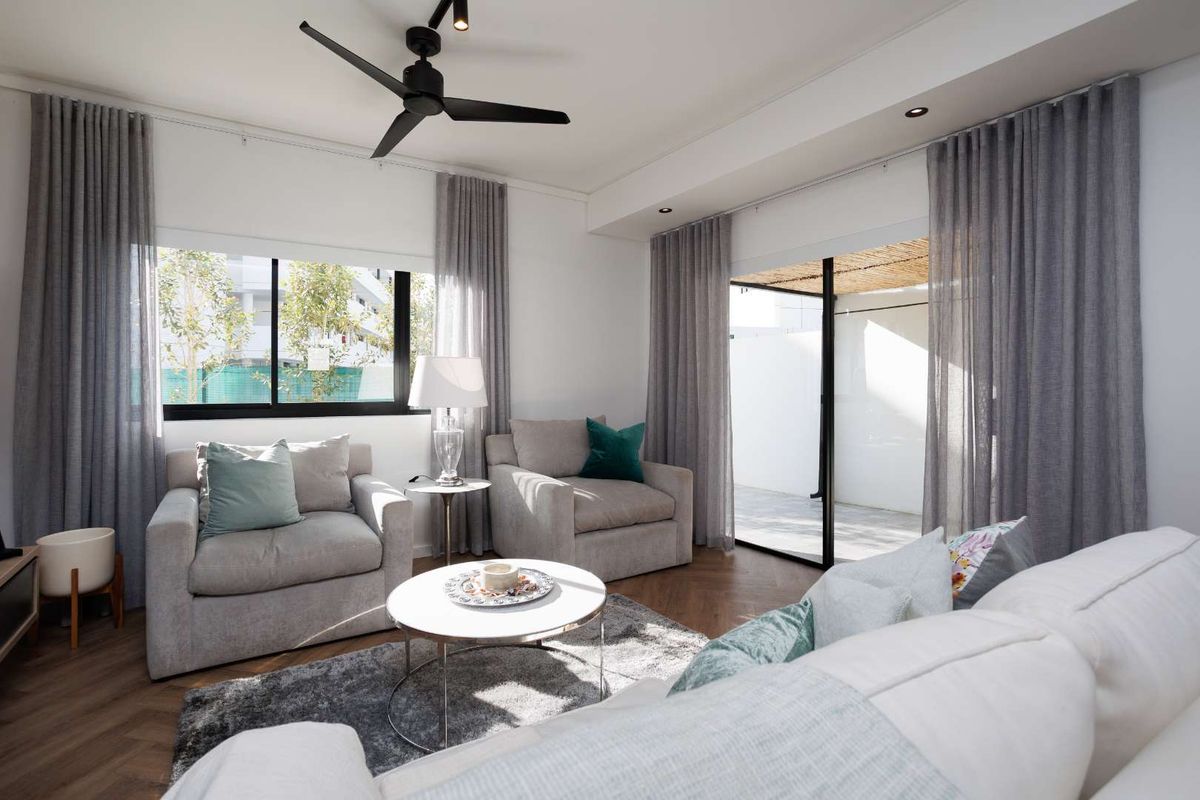 A bright and modern living room featuring herringbone flooring, recessed lighting, a ceiling fan, and large sliding glass doors leading to an outdoor patio area.