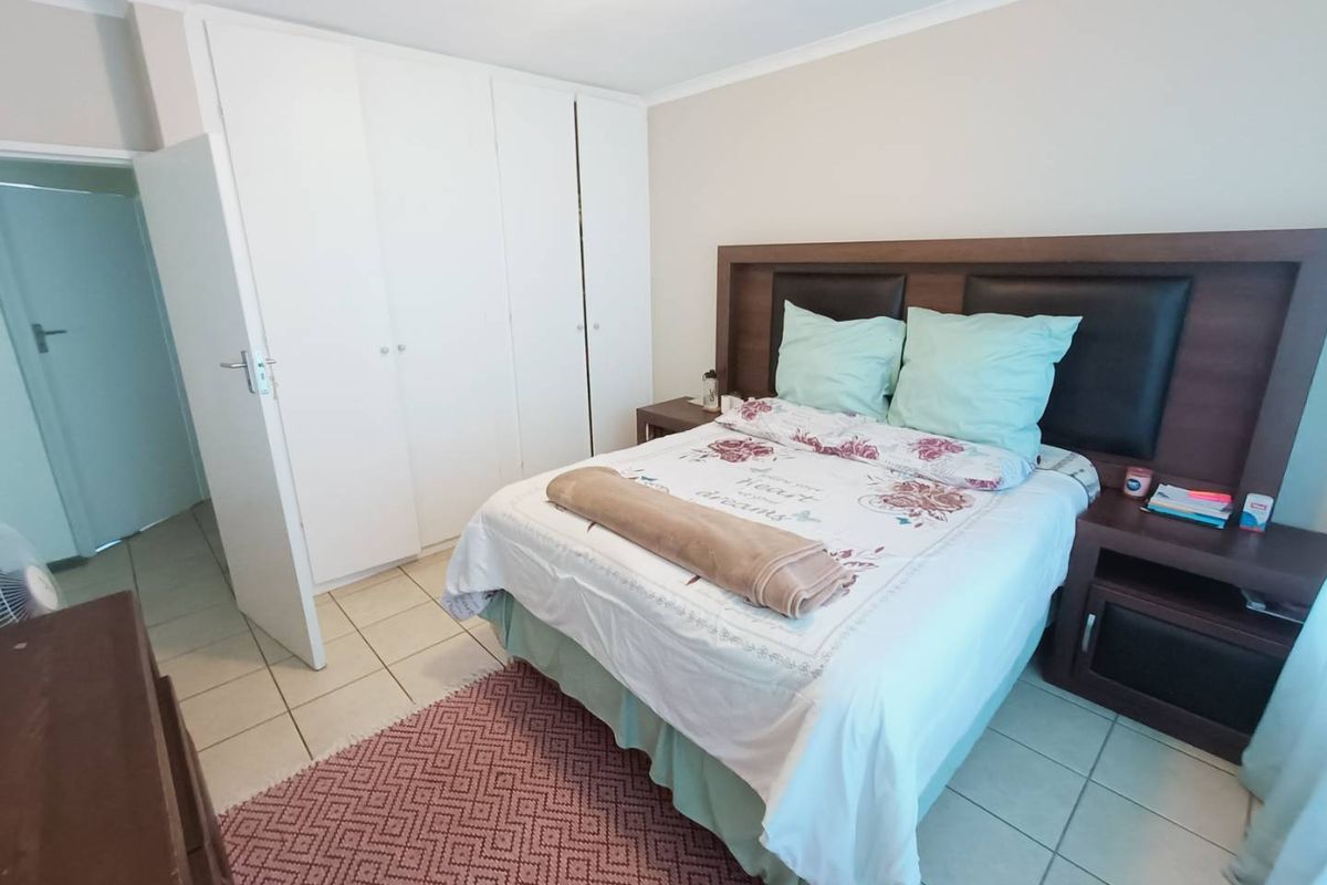 A bedroom featuring built-in cupboards and tiled flooring, providing a functional and neutral living space.