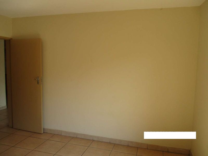 An empty bedroom featuring neutral wall paint and tiled flooring, providing a blank canvas for personalization.